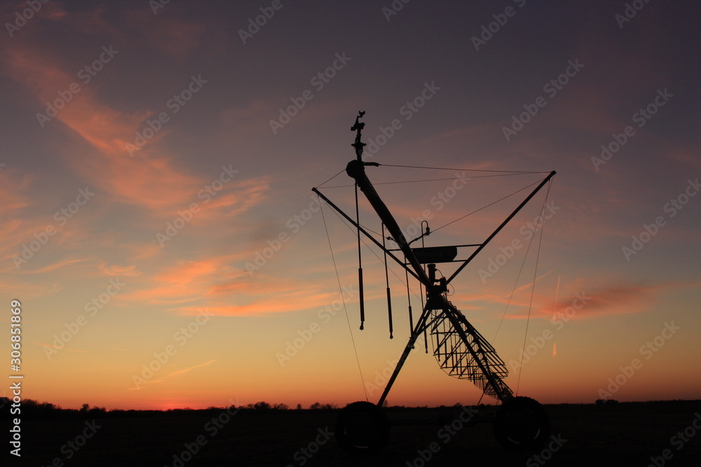 Irragation System at Sunset with a Colorful sky by a farm field.