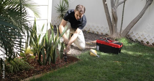 Grass Field Sprinklers Installation by Professional Caucasian Garden Systems Installator. Adjusting Lawn Sprinkler. photo