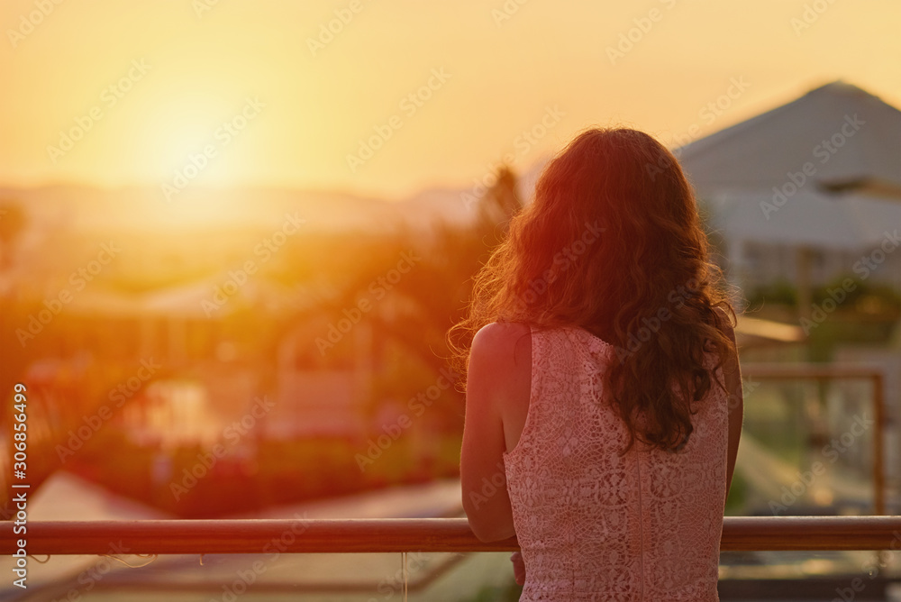 Woman silhouette on the balcony looks at sunset, mountains and nature