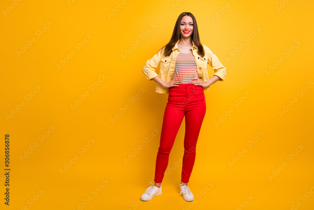 Full length body size photo of cheerful positive cute pretty nice girlfriend in trousers holding hands on waist smile toothy white foot wear isolated vivid color background Full length body size photo of cheerful positive cute pretty nice girlfriend in trousers holding hands on waist smile toothy white foot wear isolated vivid color background