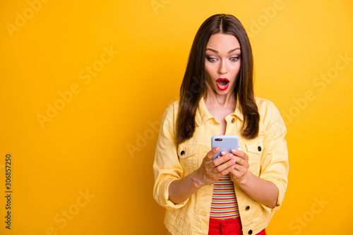 Photo of crazy mad woman scared of notification received looking into screen of telephone with eyes and mouth open wide isolated vivid color background
