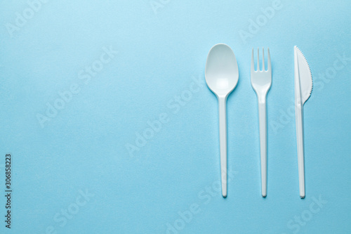 Plastic cutlery  forks  spoons and knives. Pollution of the environment with plastic and microplastics. Blue background. Copy space for text.