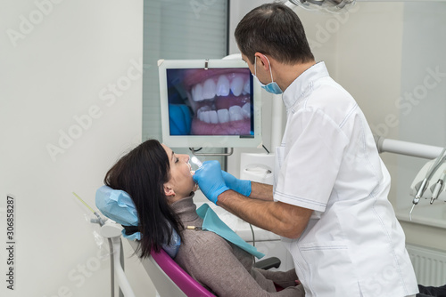 Dentist checking patient s teeth with camera in stomatology