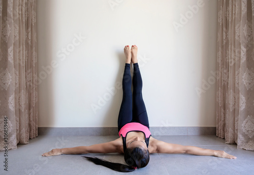 Yoga woman feet up relaxing in room on wall background