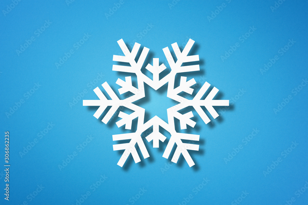Snowflake shape made from cut paper on blue background Snowflake shape made from cut paper on blue background