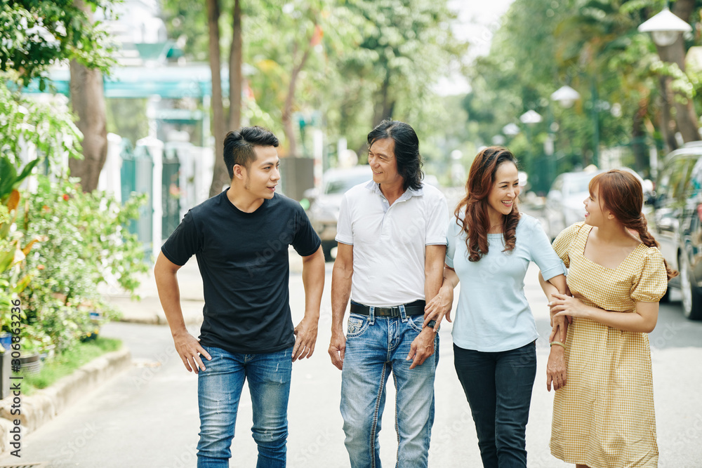 Happy mature Asian couple and their adult children walking in the street of small town Happy mature Asian couple and their adult children walking in the street of small town