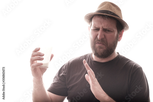 a bearded man with a glass of milk winces and does not want to drink it