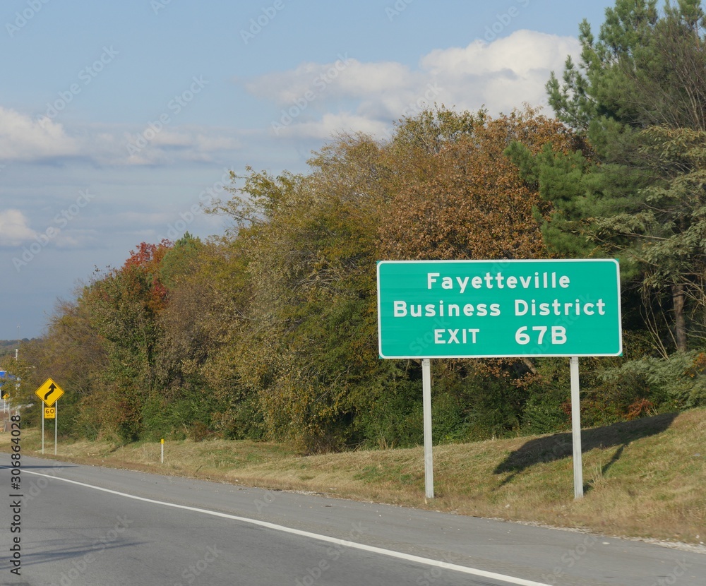Roadside sign with directions for exit to Fayetteville Business District, Fayetteville, Arkansas.