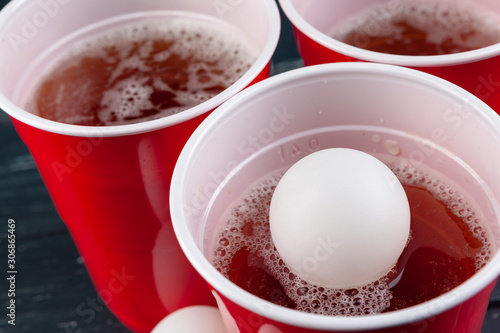 Wooden table with red cups and ball for beer pong