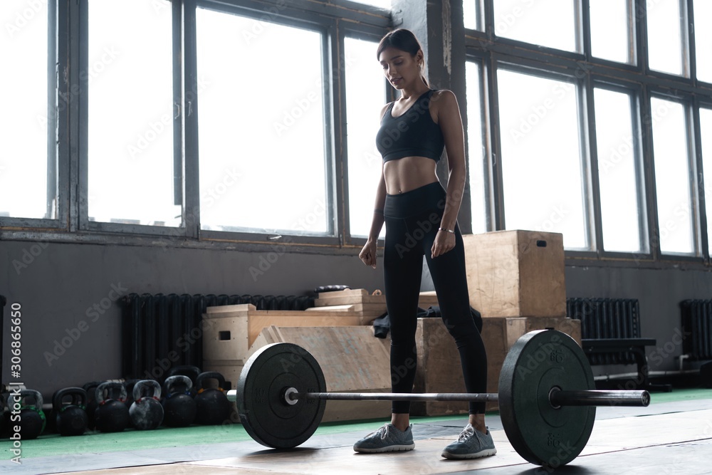 Attractive strong muscular female bodybuilder doing heavy duty squats lifting barbell at the crossfit gym. Attractive strong muscular female bodybuilder doing heavy duty squats lifting barbell at the crossfit gym.