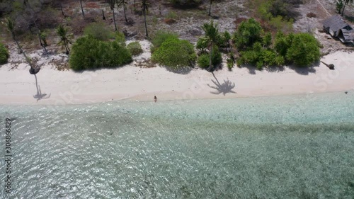 Aerial of beautiful white sand beach with a single woman - drone lifting up photo