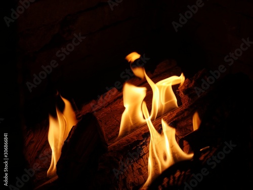Orange flames licking the logs in a fireplace  dark background