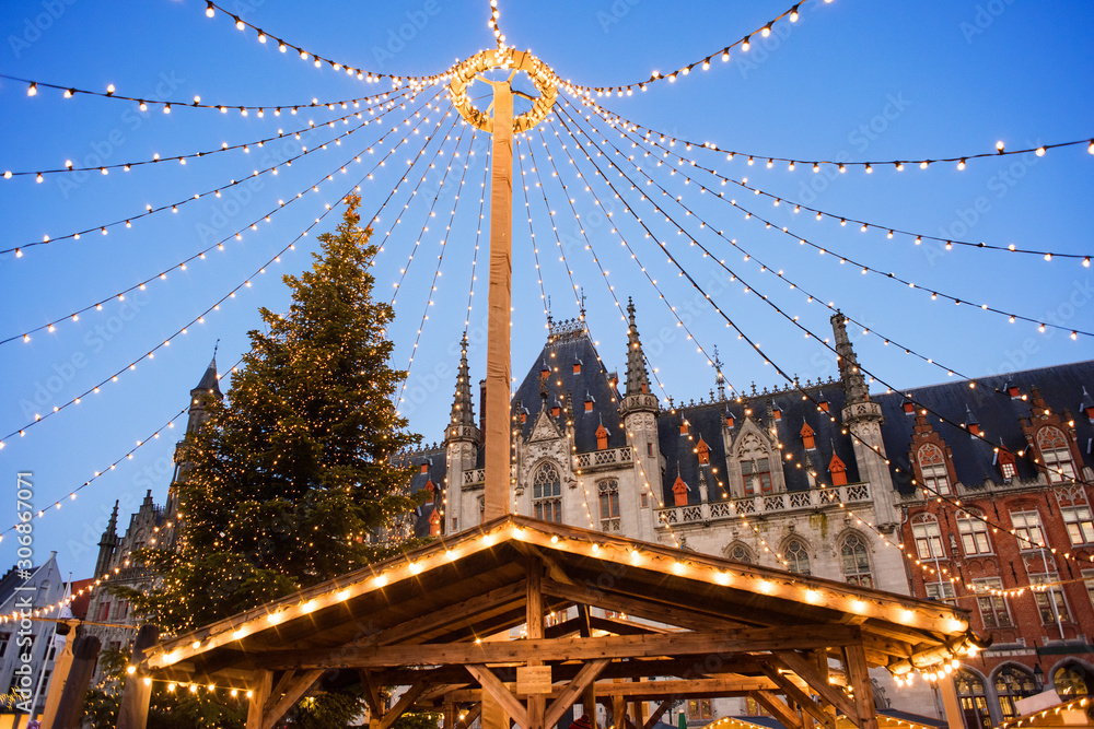 Naklejka premium Piękny jarmark bożonarodzeniowy w Europie, Brugii, Belgii. Główny plac miejski z ozdobnym drzewem i światłami. Koncepcja świątecznych targów