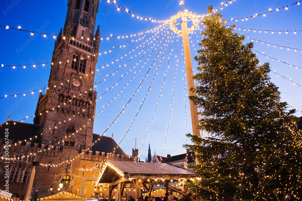 Obraz premium Tradycyjny jarmark bożonarodzeniowy w Europie, Brugia, Belgia. Główny plac miejski z ozdobnym drzewem i światłami. Koncepcja świątecznych targów