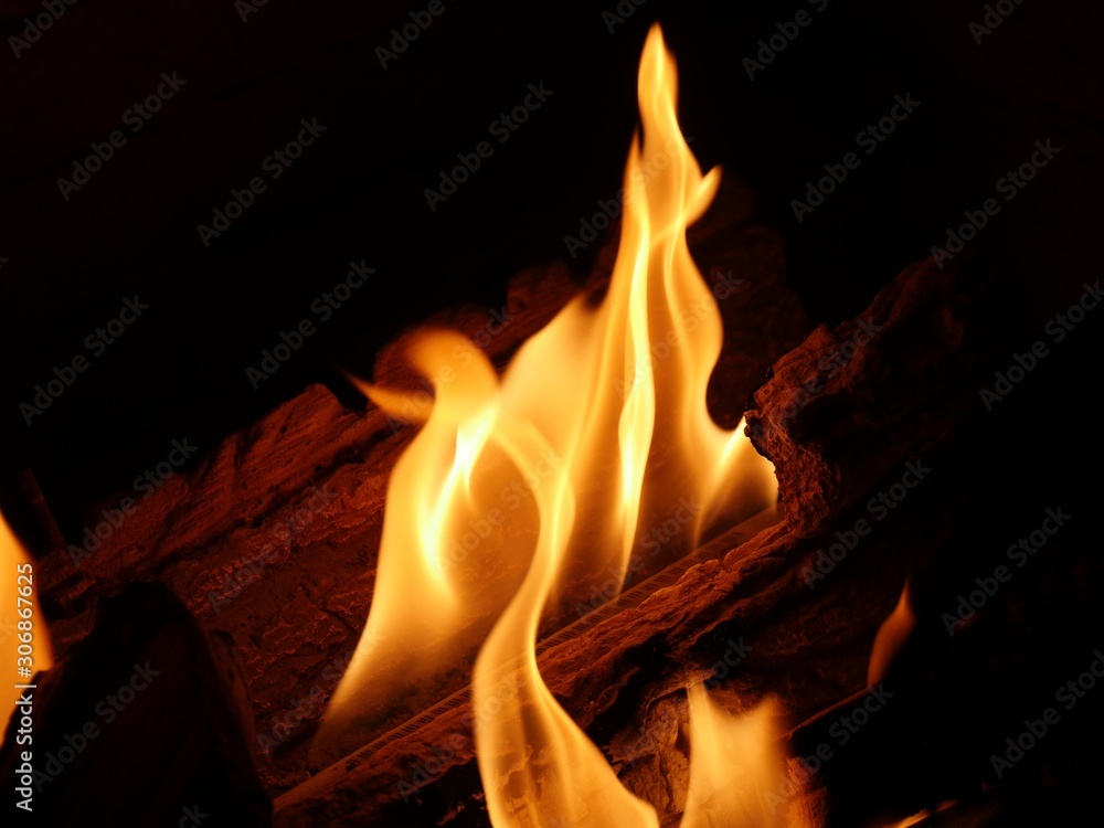 Close shot of tongues of orange flames from a fireplace, dark background Close shot of tongues of orange flames from a fireplace, dark background