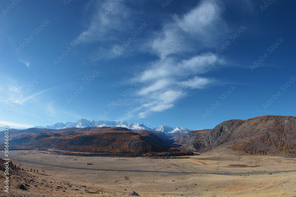 Fototapeta premium Mountain landscape. Spacious valley, snowy ridge and blue sky with white clouds.