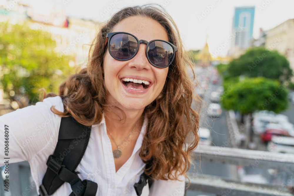 Young happy curly European girl traveler takes a selfie on the background of Yangon, the capital of Myanmar at Sule Pagoda Young happy curly European girl traveler takes a selfie on the background of Yangon, the capital of Myanmar at Sule Pagoda