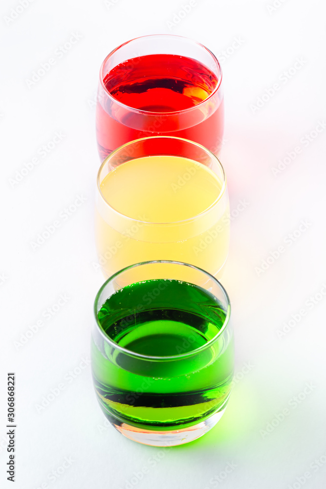 Glasses of various colors and tastes soda drink on white background. Red, yellow, green soda or sparkling water close up on white table, copy space Glasses of various colors and tastes soda drink on white background. Red, yellow, green soda or sparkling water close up on white table, copy space