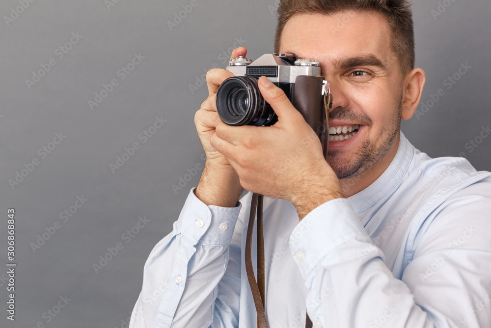 Photography Hobby. Young man studio standing isolated on grey taking photos on film camera joyful close-up Photography Hobby. Young man studio standing isolated on grey taking photos on film camera joyful close-up