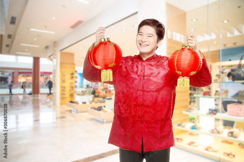 An Asian Chinese man in a cheongsam dress holding Chinese lantern An Asian Chinese man in a cheongsam dress holding Chinese lantern