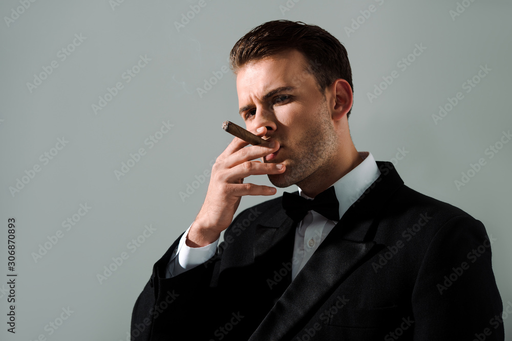 handsome and rich man smoking cigar isolated on grey handsome and rich man smoking cigar isolated on grey