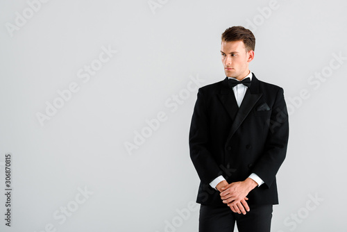 rich man in black suit gesturing while standing isolated on grey