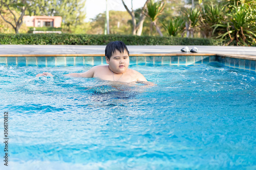 Asian boy is playing in a pool in Thailand.An obese boy swimming in the pool