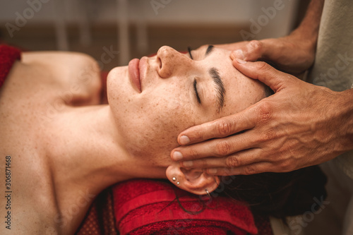 Alternative Medicine. Therapist healing lying woman smiling peaceful close-up doing head ayurvedic massage pressing on forehead