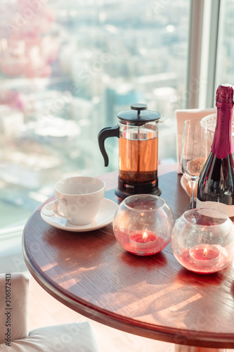 Romantic dinner. Burning candles. Tea and cups on the table on city background