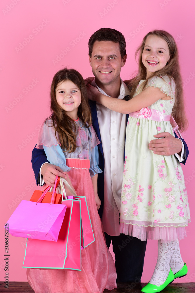 Schoolgirls in dresses and father hold packets. Shopping and presents