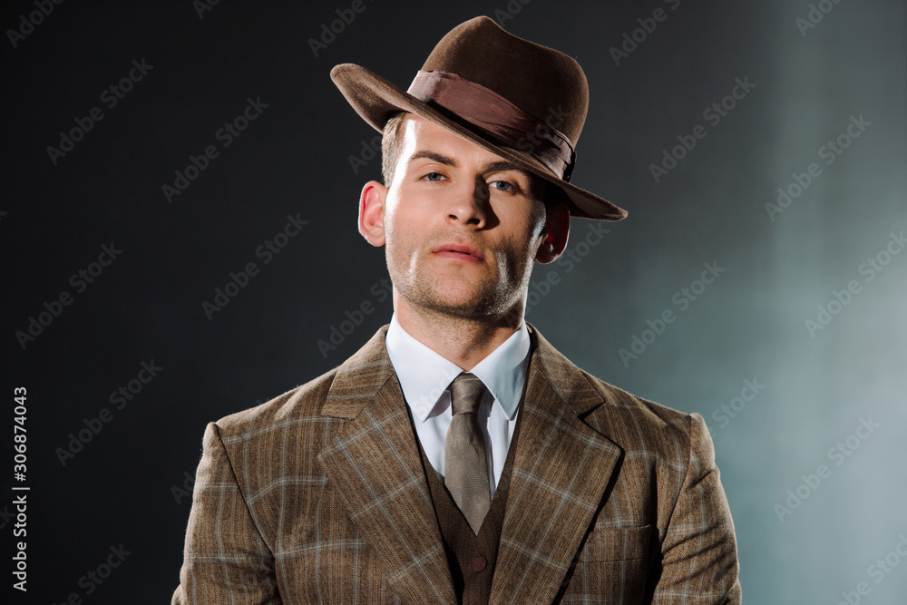 stylish gangster in hat looking at camera on black stylish gangster in hat looking at camera on black