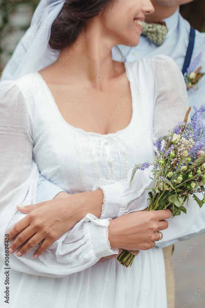 Obraz premium The first walk of the newlyweds, walking hug, love each other. girl in her hands holding flowers