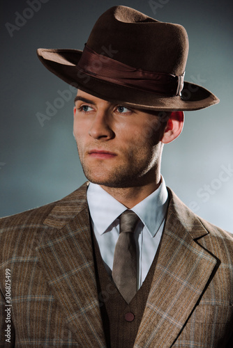 handsome man in hat and suit on black