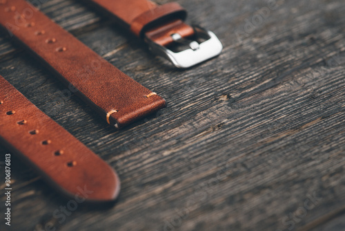 Brown leather handmade watch strap on dark rustic wooden table. Copy space for the text.