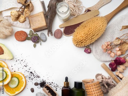 Spa and skin care concept on white background. Space for text. Top view. Body coffee scrub with natural ingredients, cucumber and orange slices, soap, serum, oil, stones, massage tool