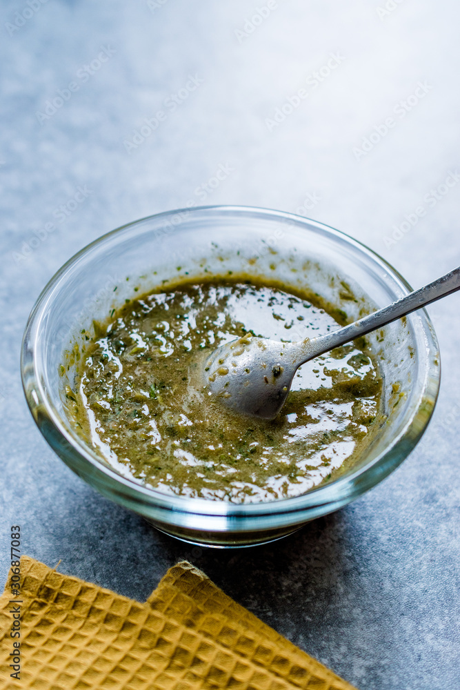 Homemade Green Herbal Salad Sauce with Plant Roots in Glass Bowl with Spoon. Homemade Green Herbal Salad Sauce with Plant Roots in Glass Bowl with Spoon.