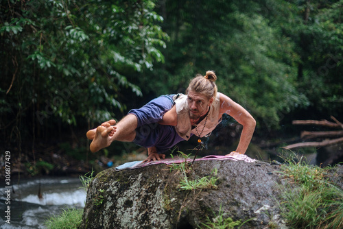 Yoga practice and meditation in nature. Man practicing near river