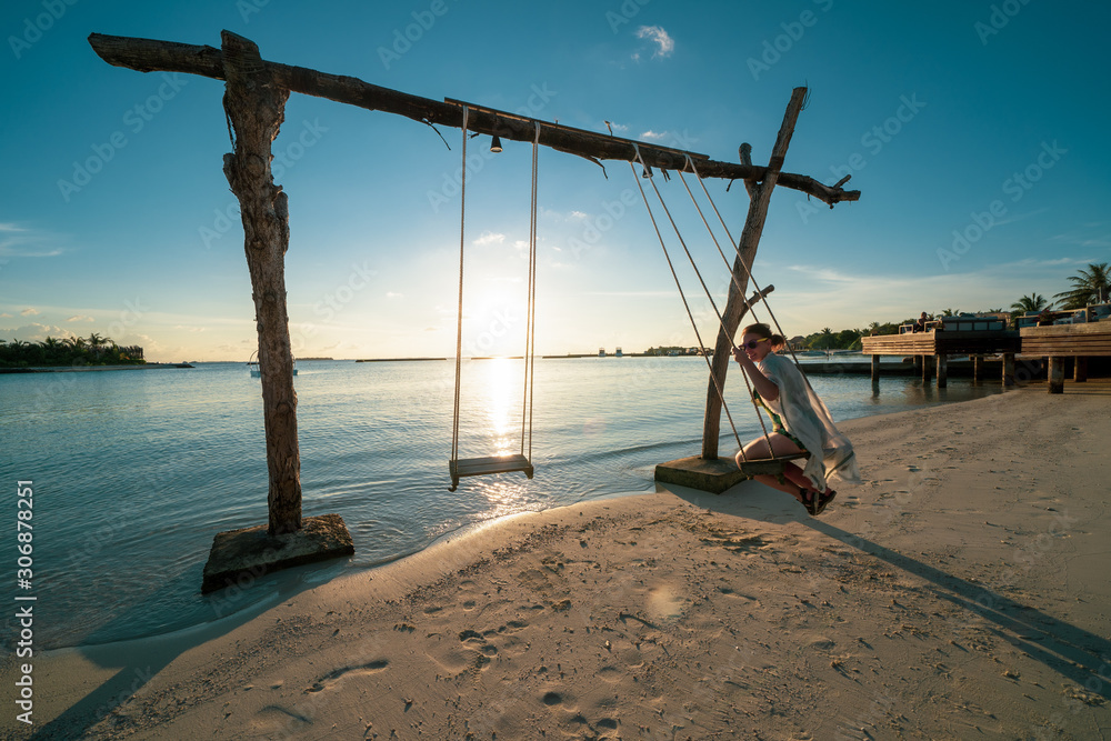 Fototapeta premium Woman uses a beach swing in the ocean at a luxury resort in the Maldives