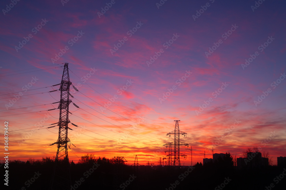Fototapeta premium Power lines on a pink sky background. Sunrise over the forest