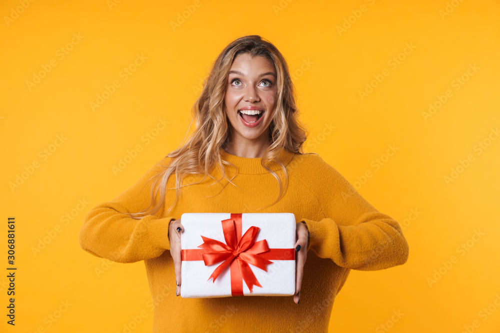 Image of gorgeous blonde woman in warm sweater smiling and holding present box Image of gorgeous blonde woman in warm sweater smiling and holding present box