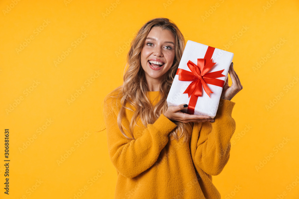 Image of attractive blonde woman in warm sweater smiling and holding present box Image of attractive blonde woman in warm sweater smiling and holding present box