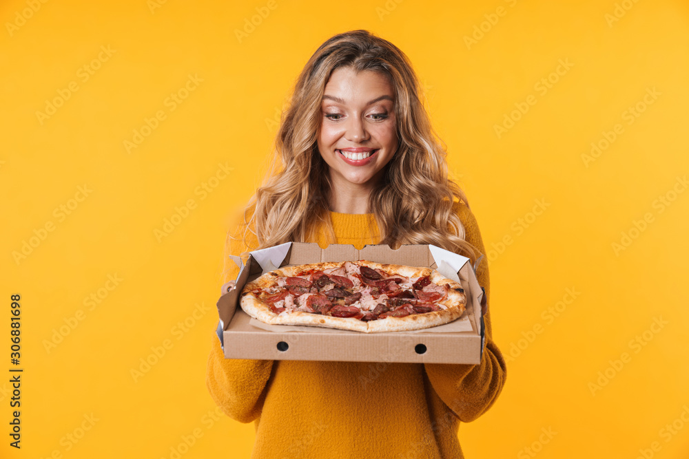Image of blonde woman in warm sweater smiling and holding pizza box