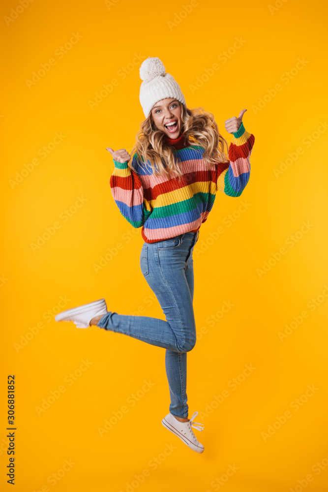 Full length image of blonde woman in winter hat showing thumbs up Full length image of blonde woman in winter hat showing thumbs up
