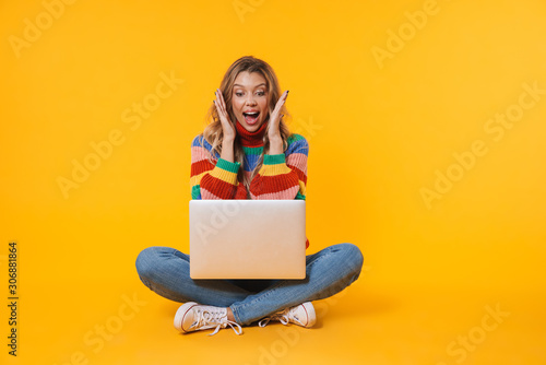 Image of blonde woman using laptop computer while sitting on floor