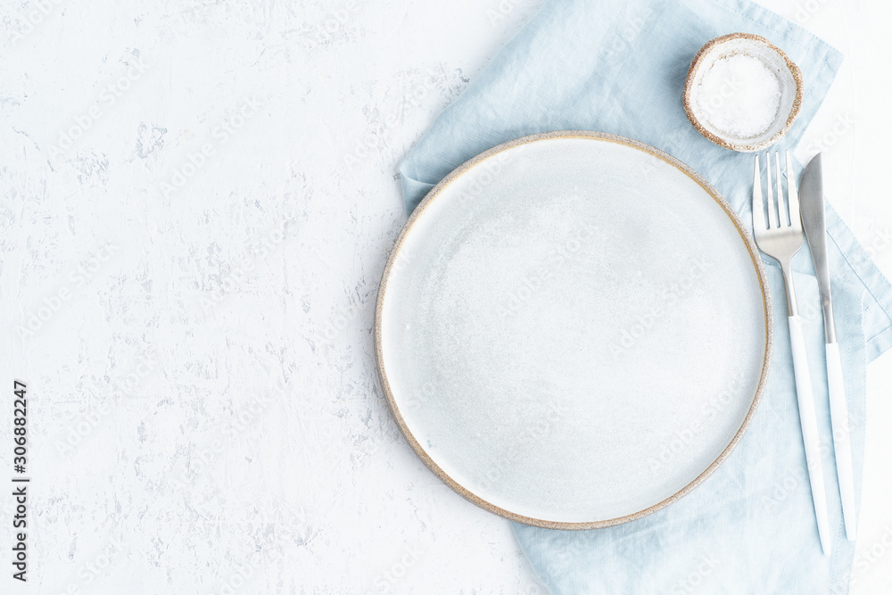 Clean empty white ceramic plate, fork and knife on white stone table, copy space, mock up, top view. Concept for menu Clean empty white ceramic plate, fork and knife on white stone table, copy space, mock up, top view. Concept for menu
