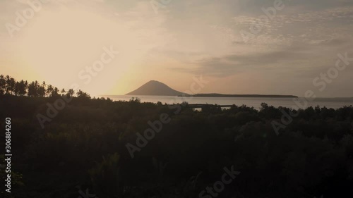 Volcano in the middel of the ocean seen from land during sunset by drone with Palm tree silhouettes photo