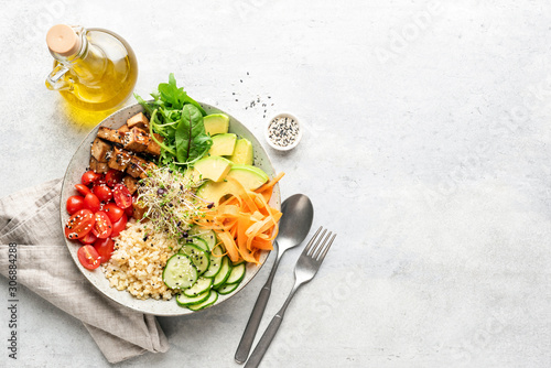 Vegetarian Vegan salad bowl or buddha bowl with grains, tofu, avocado, vegetables and greens. Balanced meal on grey concrete background. Top view, copy space