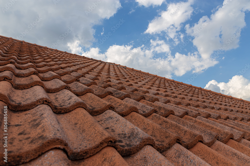 roof top on sky background. Close up of brown clay roof tiles. Red old dirty roof. Old roof tiles. Construction equipment build a house.