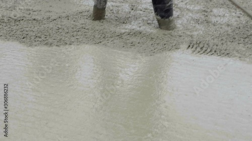 Workers work on building site, ground works. Detail of casting pump concrete to foundations of family house. Concrete mix pump works on baseplate, sky in background