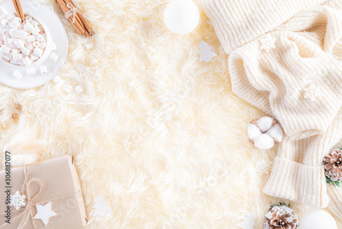Winter composition. Gift box marshmallow cup, Christmas ball snowflakes, anise stars, beige sweater on cream colour knitted blanket and fluffy background. Flat lay top view copy space.